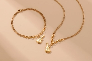 Detailed view of a gold-plated double-layer necklace and bracelet set with guitar pendants