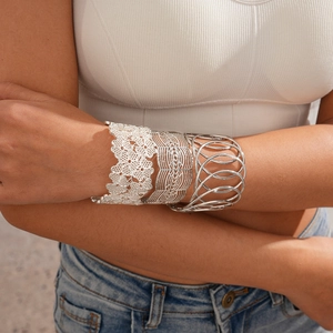 Close-up of three silver open bangles with floral cutouts and geometric woven textures