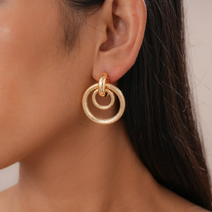 Close-up of matte and polished gold double hoop earrings worn on a female model