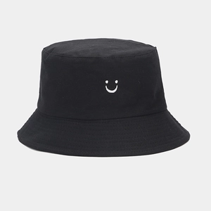 Detail of black cotton bucket hat with a white embroidered smile face and flat brim