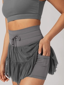 Detail view of high-waist pleated sports skirt with side pocket and layered mesh design