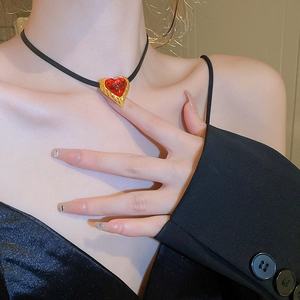 Detail of vintage red heart pendant choker with gold metal frame worn by a model