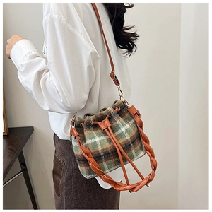 Detailed side view of vintage green checkered wool bucket bag with leather strap and weaving