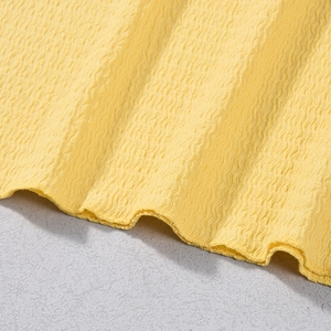 Détail du tissu jaune de robe dos nu montrant la texture 3D smockée et la finition de l'ourlet