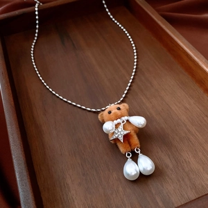 Close-up of a flocking bear necklace with water-drop pearls and sparkling star charms