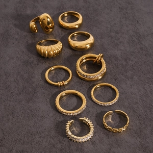 Detailed view of 10pcs gold-plated titanium steel rings with zircon on stone background