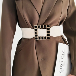 Detail of a white elastic wide belt with a luxury square black-gold rhinestone buckle