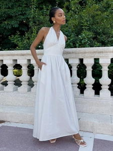 Detail of white cotton maxi dress featuring deep V-neck halter and side pockets