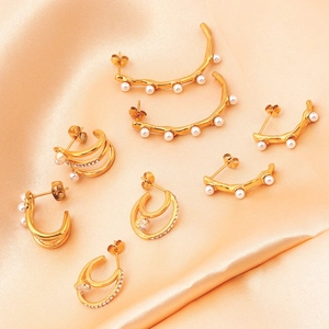 Détail de boucles d'oreilles vintage dorées 18K avec perles et zircons sur de la soie