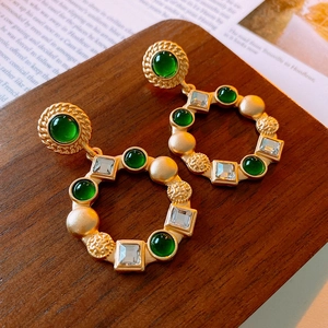 Detailed close-up of vintage gold earrings with green gems and square crystals