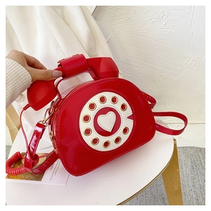Close-up of a red vintage telephone-shaped crossbody bag with glossy patent leather finish