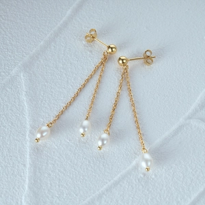 Detailed macro shot of 925 silver golden double chain earrings with baroque drop pearls