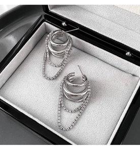 Detail of silver tassel earrings with layered chains and zircons in a black jewelry box