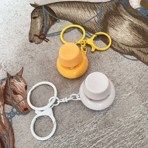 Close-up of circular fidget button keychains in yellow, orange, and white plastic finish