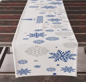 Close-up of white linen table runner with blue and silver snowflakes and Merry Christmas text
