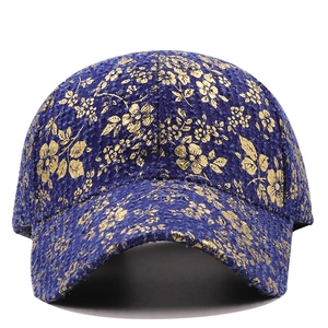 Detailed view of dark blue baseball cap featuring vintage gold floral embroidery patterns
