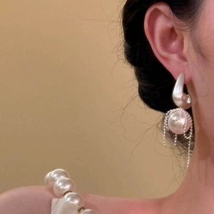 Elegant silver bow pearl earrings with long diamond tassel fringes on a female model