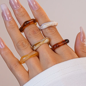 Gros plan de bagues en acrylique superposées aux motifs ambre et écaille sur la main