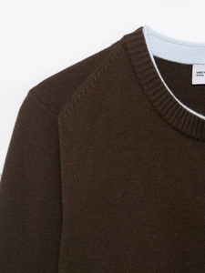 Detail of dark brown knit sweater neckline with light blue contrast piping and inner tag