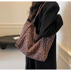 Fashionable leopard print canvas tote bag with leather trim worn over the shoulder