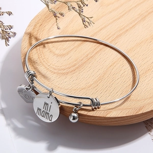 Bracelet coeur en acier argenté avec gravure Love mi mama sur un plateau en bois
