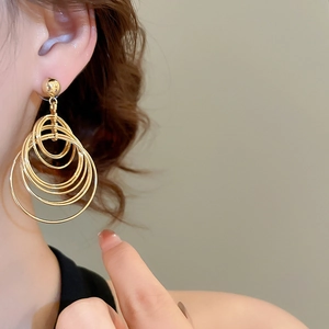 Detail shot of a model wearing tiered gold geometric hoop earrings with concentric rings