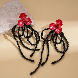 Detail view of retro flower earrings with red petals and black beaded tassel accents