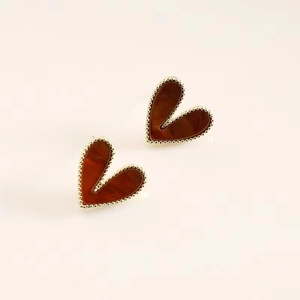 Detail of heart-shaped earrings in reddish brown resin with gold-tone beaded edging