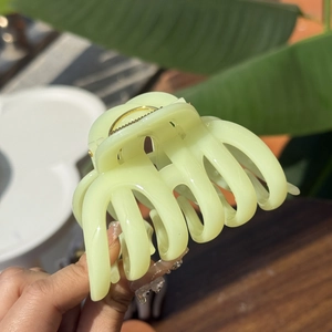 Detail view of a large light green pumpkin hair claw clip shown in an open position
