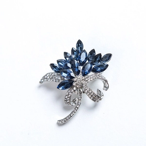 Detailed view of flower brooch featuring blue crystals and shimmering rhinestones