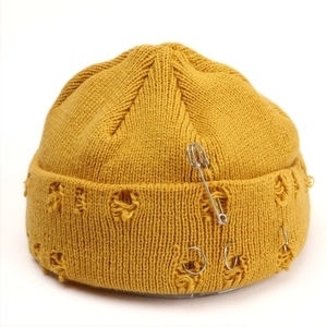 Yellow distressed knit beanie with silver rings and safety pins in a trendy hip-hop style