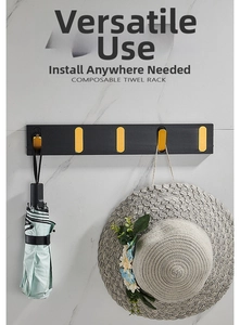 Close-up of wall-mounted black and gold foldable hooks holding an umbrella and a hat