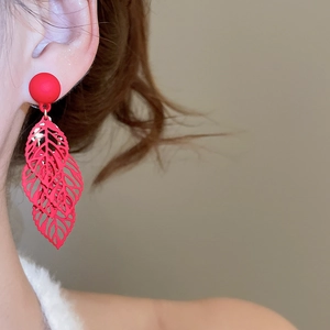 Close-up of red hollowed leaf pendant earrings on model with matte finish details