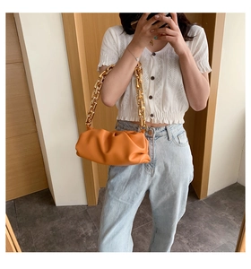 Detailed view of vibrant orange cloud bag featuring a thick gold chunky chain strap