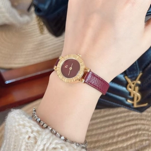 Chic lifestyle shot of a woman wearing a gold round watch with burgundy leather strap