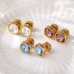 Gros plan de boucles d'oreilles dorées avec cristaux carrés bleus, roses et blancs