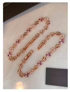 Macro view of rose gold flower bracelet with zircon stones and white pearls on marble