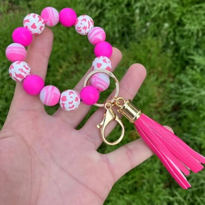 Close-up of pink silicone bead keychain with leopard print accents and long leather tassel