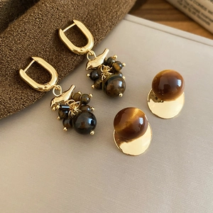 Detail view of 18k gold plated bird earrings featuring tiger eye stone and beaded tassels