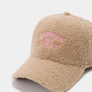 Close-up of pink 'TANNED and TIPSY' embroidery on khaki teddy fleece baseball cap