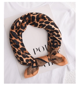 Detail of leopard print silk-like square scarf knotted on a white tee with card