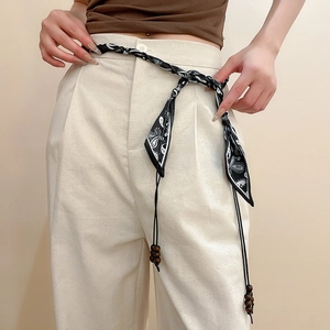 Detail of bohemian silk scarf waist belt with floral print, tassels, and wooden beads
