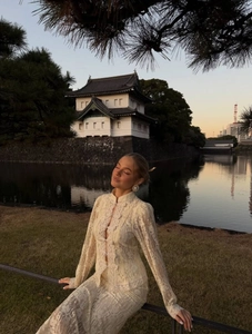 Elegant off-white lace two-piece set with Chinese frog buttons by a scenic lake sunset