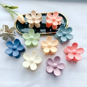 Flat lay of colorful matte flower hair claws in pastel tones on a white textured background