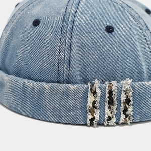 Detail of washed denim miki hat featuring leopard print patches and metal eyelets