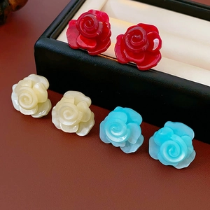 Vue détaillée de boucles d'oreilles roses en résine rouge, beige et bleu sur plateau