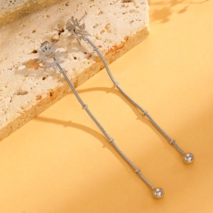 Detail of silver long tassel earrings with sun design on a textured stone surface
