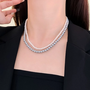 Close-up of double-layer necklace with white and silver-grey pearls on a model