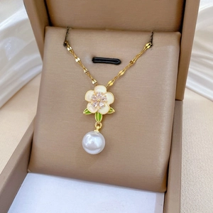 Détail d'un collier en acier titane floral avec pendentif perle et cristaux dans sa boîte