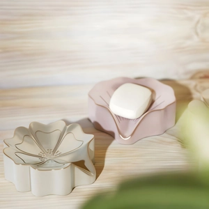 Détail de porte-savons en silicone en forme de fleur rose et blanc avec bordure dorée